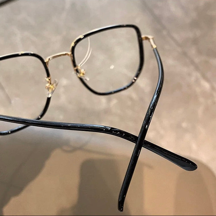 Black and gold eyeglasses on a reflective surface