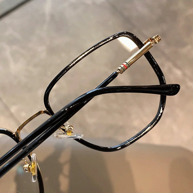 Close-up of a black eyeglass frame with gold accents on a neutral background