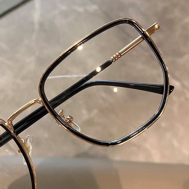 Eyeglasses with black and gold frame over a neutral background